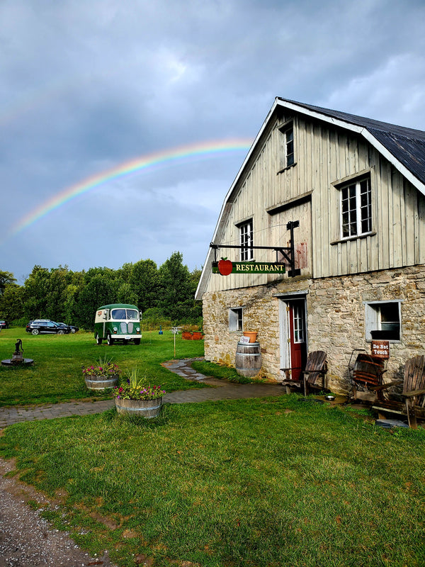 A picture of the County Cider tasting room with a rainbow in the background
